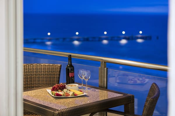 bottle of wine, cheese and biscuits on balcony in evening with views of ocean at beachfront hotel in Glenelg, SA
