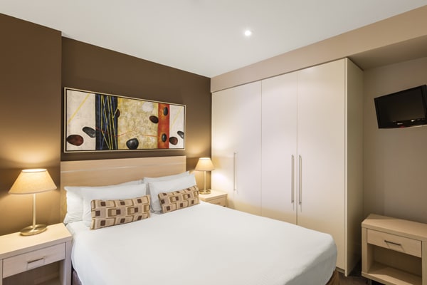 queen size bed in 2 bedroom apartment with air con, Wi-Fi access and in room TV with Foxtel at Oaks Plaza Pier hotel in Glenelg, South Australia