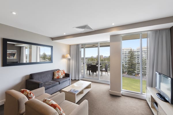 spacious living room with comfortable couches, free Wi-Fi access and private balcony outside 2 Bedroom Apartment at Oaks Plaza Pier hotel in Glenelg, South Australia