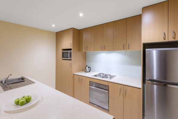 large kitchen with plenty of cupboards for storage, big fridge, freezer, oven, dishwasher and microwave in 1 bedroom hotel apartment at Oaks on Lonsdale, Melbourne CBD, Victoria, Australia