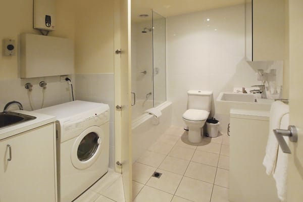 en suite bathroom with clothes washing machine and dryer in laundry room of 3 Bedroom Apartment near Flinders Street Railway Station in Melbourne, Victoria, Australia