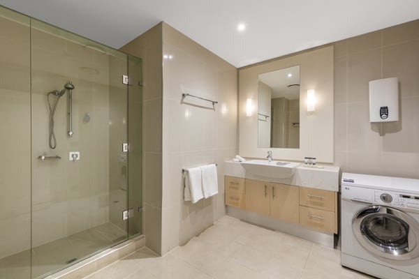 large en suite bathroom with washing machine, shower and clean towels in Hotel Apartment at Oaks On Lonsdale in Melbourne city, Victoria, Australia