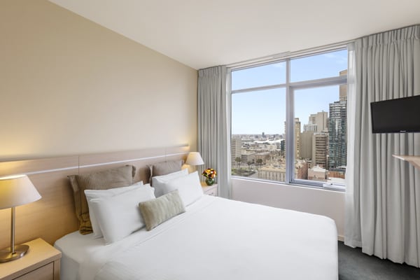 comfortable double bed in air conditioned serviced apartments Melbourne CBD bedroom with Wi-Fi, Foxtel and big windows with great views of Melbourne city in Studio Apartment at Oaks On Lonsdale