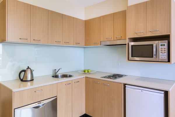 kitchenette with kettle, dishwasher, cutlery, bar fridge, microwave and stove hot plate for cooking in Studio Apartment at Oaks On Lonsdale hotel in Melbourne city, Victoria, Australia