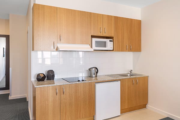 double bed in air conditioned Studio Apartment with microwave and kettle in kitchenette at Oaks on Market hotel in Melbourne city, Victoria, Australia