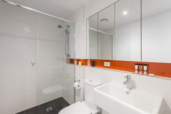 clean en suite bathroom with large disabled access shower, toilet and large mirror in 1 bedroom apartment with Wi-Fi at Oaks South Yarra hotel, Melbourne city, Victoria, Australia