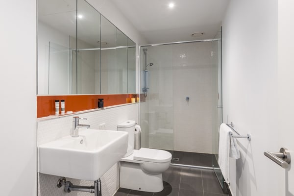 clean en suite bathroom with spacious disabled access shower, toilet, large mirror and fresh towels in Studio Apartment at Oaks South Yarra hotel, Melbourne city, Victoria, Australia