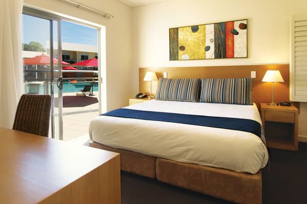large, comfortable double bed with clean sheets next to desk for corporate travellers to do work while visiting Broome, WA