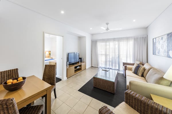 spacious living room with Foxtel on TV, air conditioning, ceiling fan and dining table in 1 bedroom hotel apartment in Western Australia