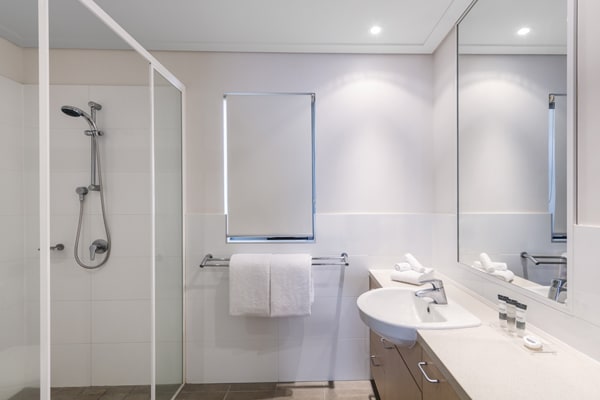 shower in clean en suite bathroom of popular hotel room in Broome, WA with toilet, fresh towels and large mirror