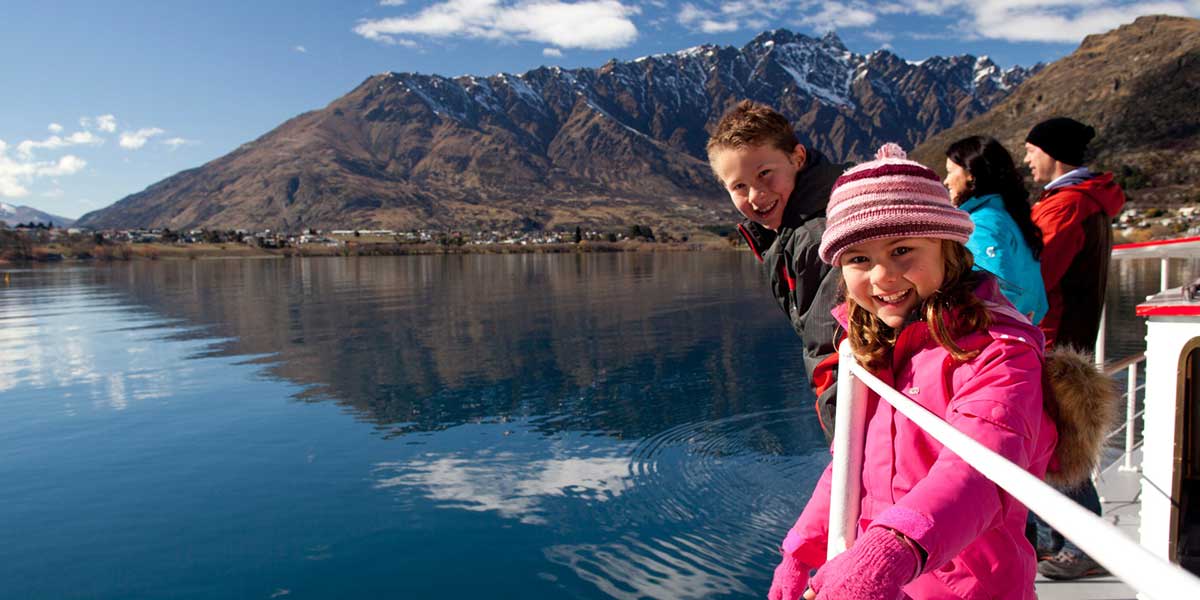 Family bonding and enjoying the cruise on Lake Wakatipu Ziptrek Ecotours with view from the hillside of Queenstown