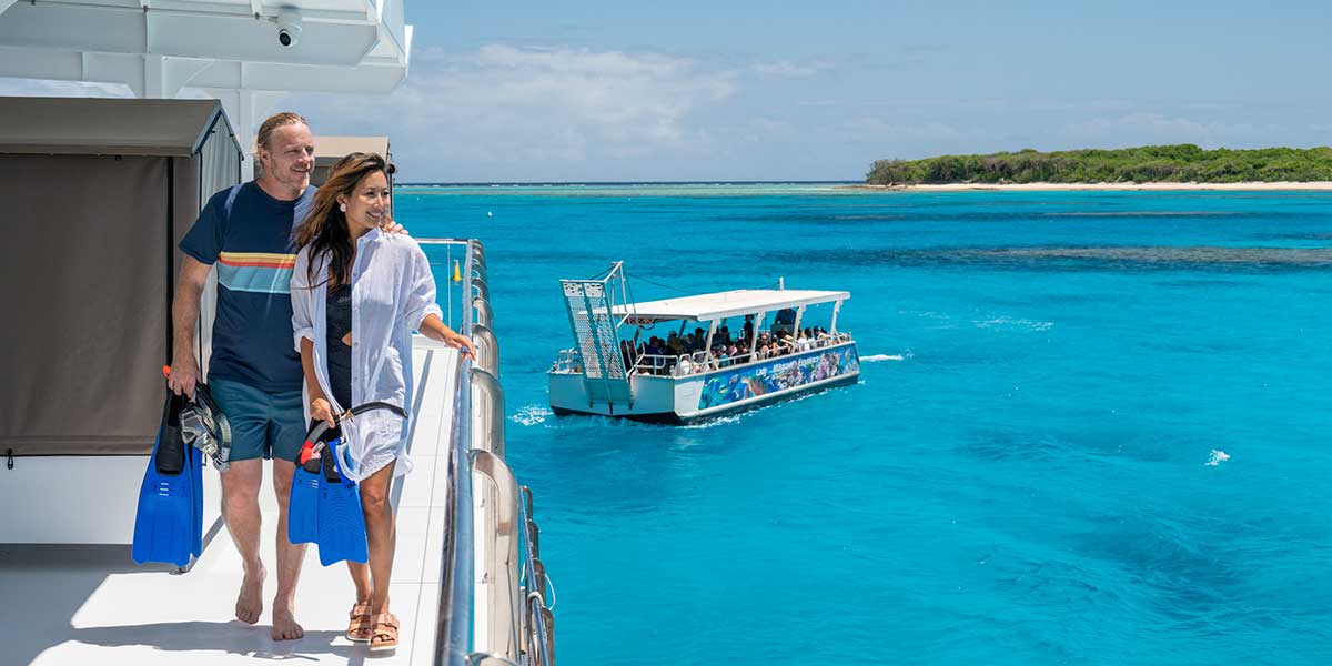 Couple on a boat enjoying the view of magical Lady Musgrave Island and surrounded by a huge turquoise lagoon
