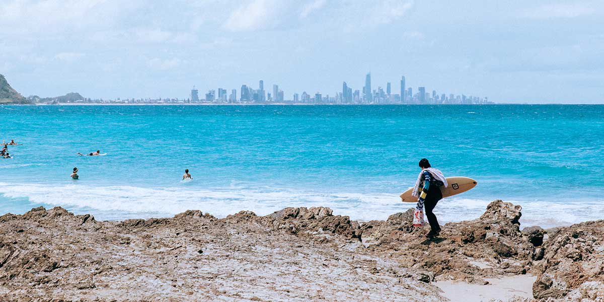 Crystal clear waters of Currumbin Beach with surfers enjoying the easy-to-catch waves by the alley