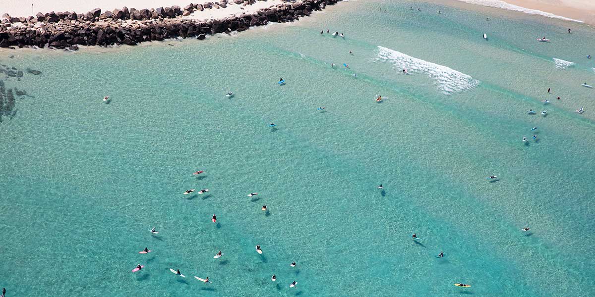 Bird's eye view of the crystal clear waters of the Duranbah Beach with surfers enjoying the waves