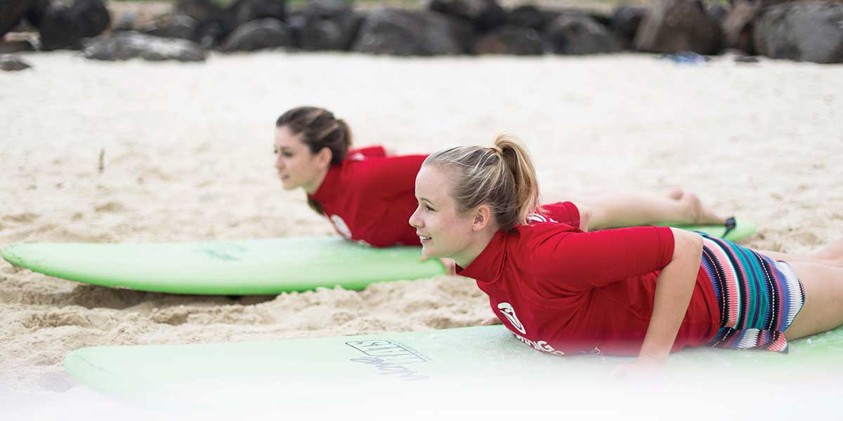 Two girls practicing the surf boards before they catch the waves
