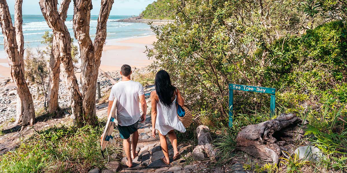 Couple going down the peak of the Tea Tree Bay at Noosa National Park in Queensland