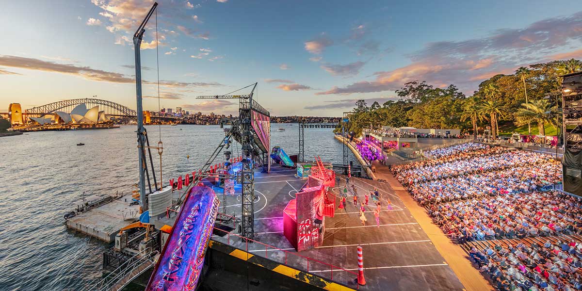 Handa Opera's pop-up show with the sun sets behind the stunning city skyline of Sydney Harbour while the stage comes alive with a vibrant, electrifying show.