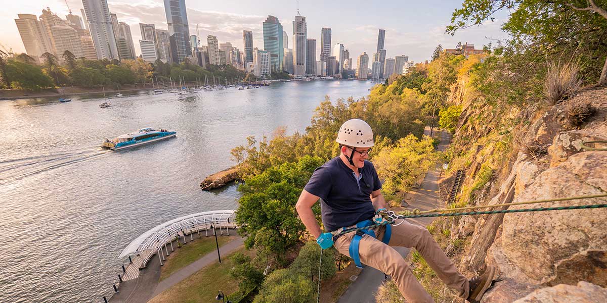A man abseiling at Kangaroo Point Cliffs with spectacular view of river in Brisbane Queensland
