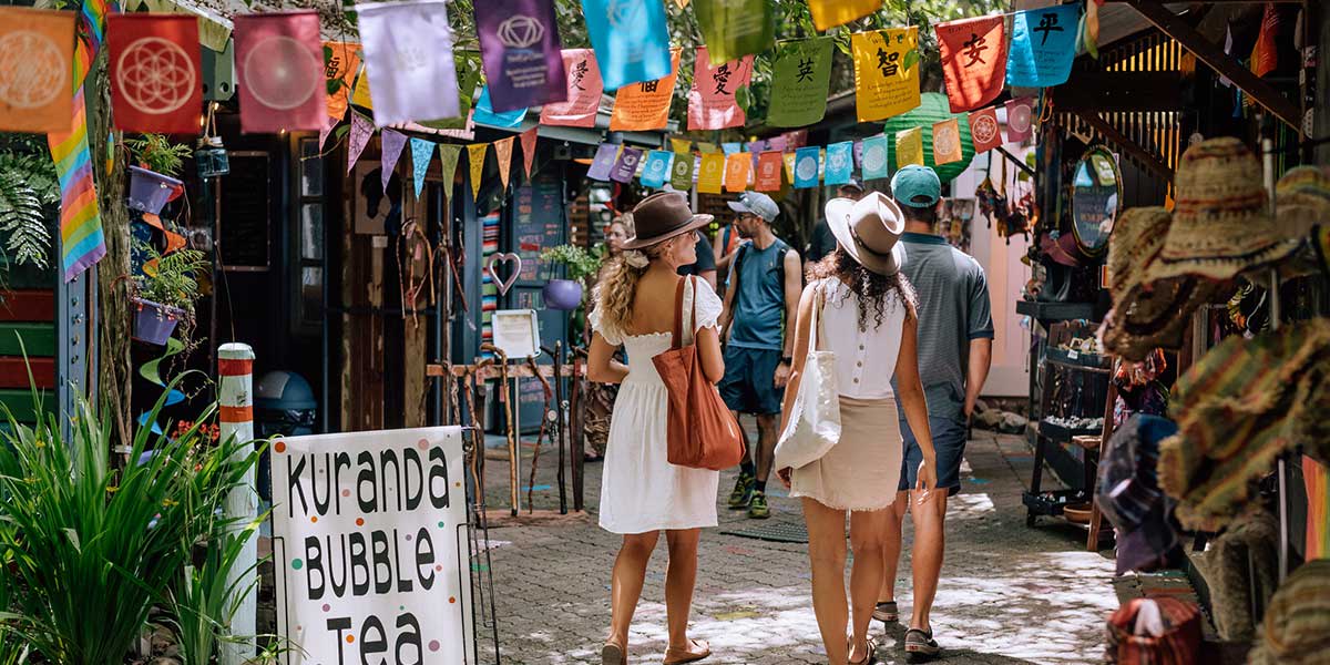 Tourists walk along the Kuranda Rainforest Markets exploring the left and right hubs of arts and crafts