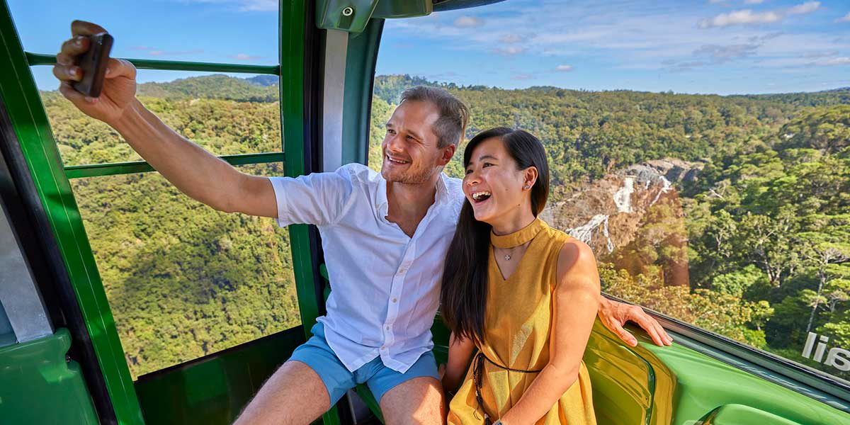 A couple taking a selfie inside the Skyrail Rainforest Cableway with stunning views of the rainforest