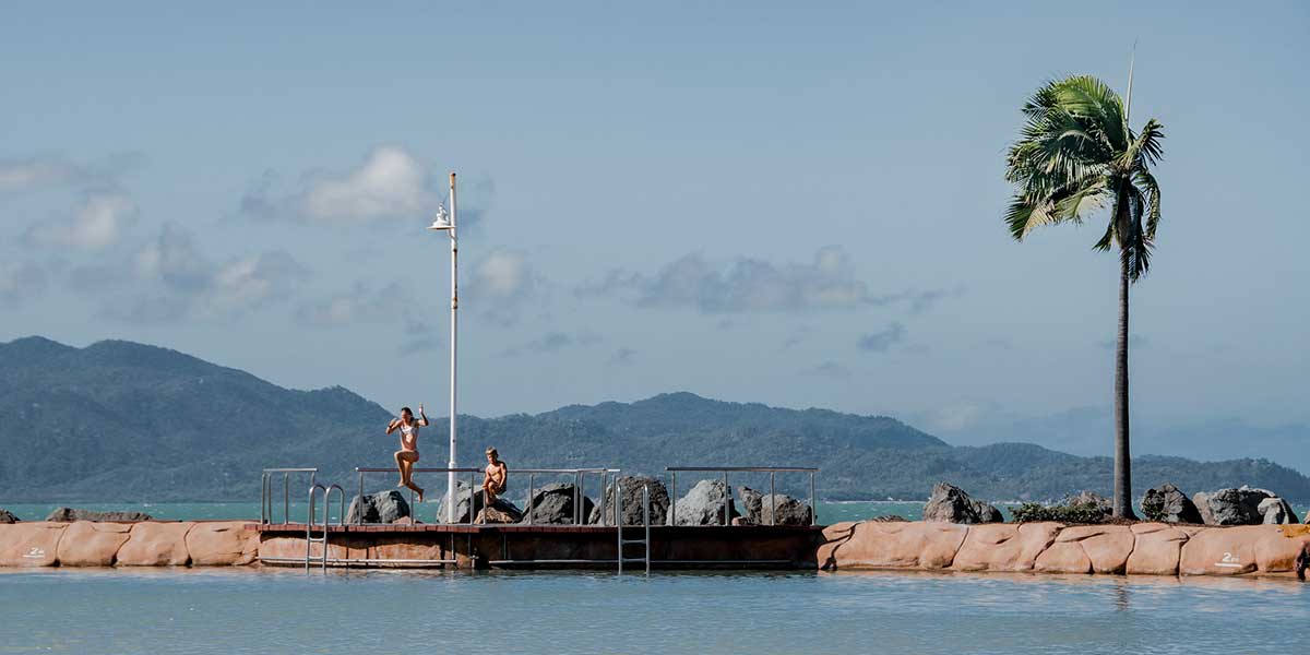 The Strand's picturesque beachside foreshore in Townsville with swimmers seen jumping off the short cliff