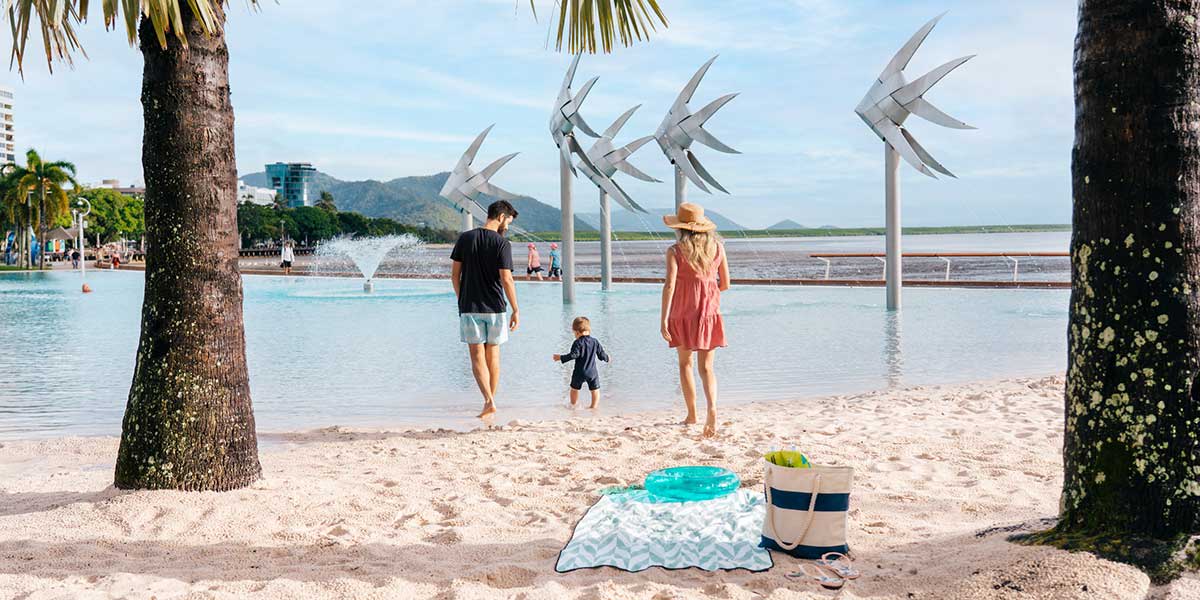 A family enjoying the white sand and blue waters of Cairns Esplanade Lagoon at Tropical North Queensland