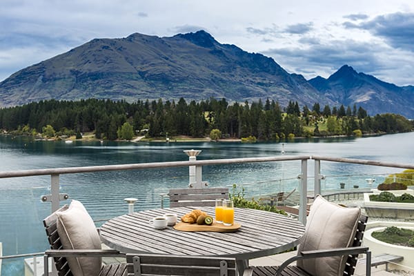 delicious hotel breakfast menu option with orange juice on table on private balcony at Oaks Club Resort hotel in Queenstown with The Remarkables mountain range and Lake Wakatipu in background