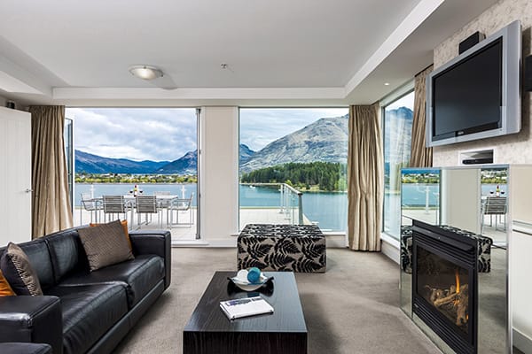 Queenstown ski resorts with Wi-Fi spacious living room, fireplace, Sky TV, leather couches, and large private balcony with views of Lake Wakatipu and The Remarkables mountain range in New Zealand