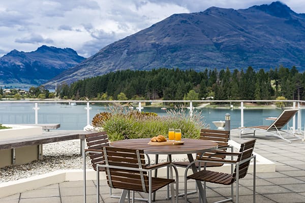 spacious private hotel balcony with vegetarian menu options on table and views of Lake Wakatipu at Oaks Club Resort in Queenstown, New Zealand