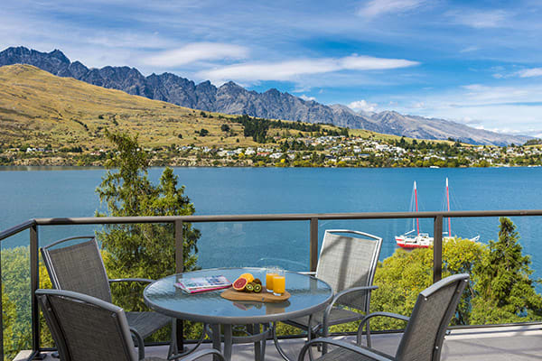 vegetarian breakfast options on table on private balcony of 1 Bedroom Apartment with views of boats and tourists on holiday enjoying activities on Lake Wakatipu in Queenstown, New Zealand