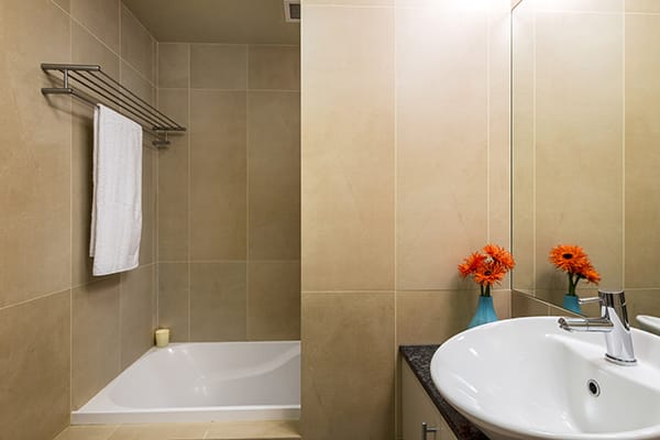 clean en suite bathroom with bath tub, shower, toilet and fresh towels for guests staying in 1 Bedroom holiday apartment at Oaks Shores hotel in Queenstown, New Zealand