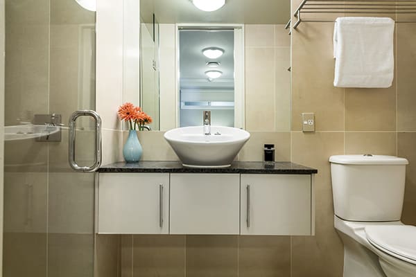 clean en suite bathroom in 2 bedroom holiday apartment with big mirror, fresh towels, toilet and disabled access shower at Oaks Shores hotel in Queenstown, New Zealand