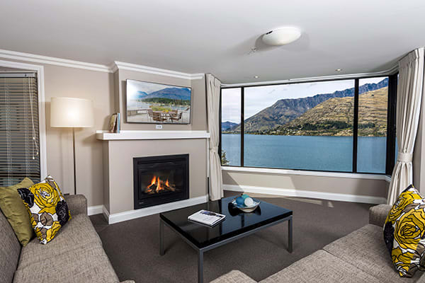 warm fireplace in living room of child friendly 2 Bedroom Holiday Apartment with Wi-Fi access for kids at Oaks Shores hotel in Queenstown, New Zealand