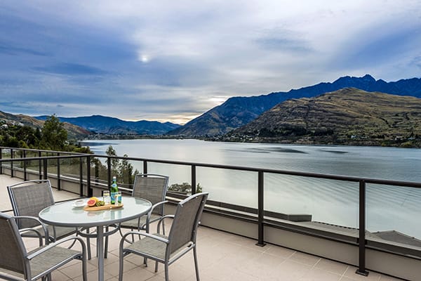 spacious penthouse balcony with vegetarian food menu option on table and panoramic views of Lake Wakatipu in Queenstown, New Zealand