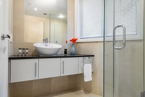 clean en suite bathroom with shower, toilet, large mirror, heating and fresh towels in 4 Bedroom Penthouse holiday accommodation at Oaks Shores hotel in Queenstown, New Zealand