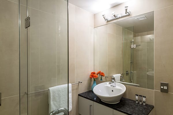 en suite bathroom with big mirror, clean towels, toilet and disabled access shower in 4 Bedroom Penthouse holiday apartment at Oaks Shores hotel in Queenstown, New Zealand