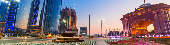 Abu Dhabi city at sunset with flower gardens and temples along busy streets filled with overseas tourists