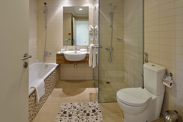 en suite bathroom with bathtub, toilet, shower and clean white towels in Deluxe 1 Bedroom holiday apartment at Oaks Liwa Heights hotel in Dubai, United Arab Emirates